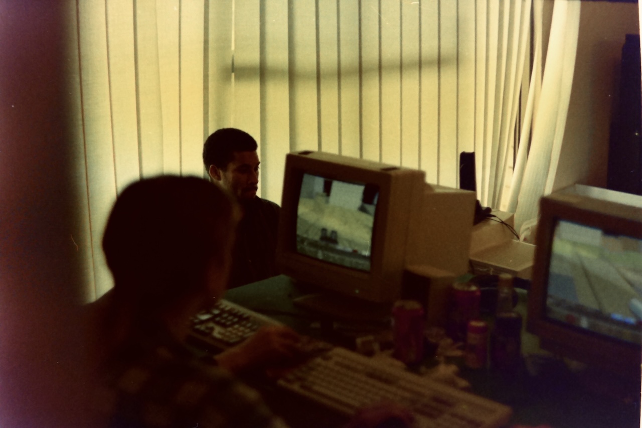 Two people sit playing Team Fortress, the original mod for Quake, at a LAN party.